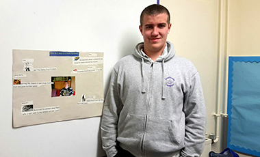 17-year-old lad standing next to a poster of how he sees a 'Fairer Scotland' by 2030.